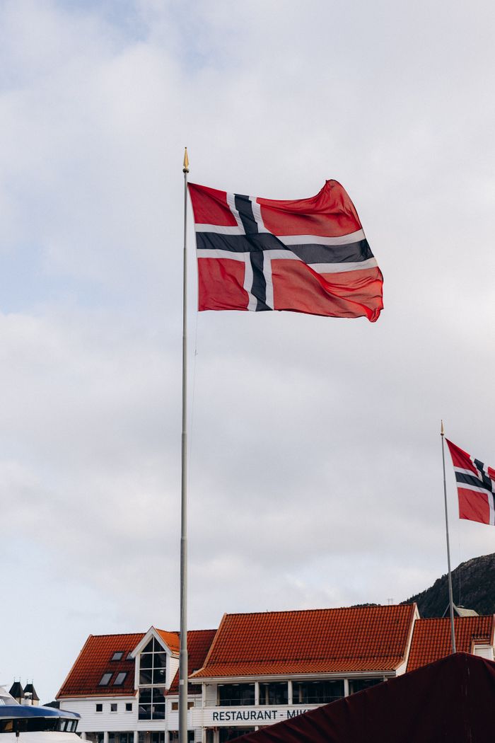 Norwegian flags fluttering in the breeze in Bergen, Norway, with buildings in the background.